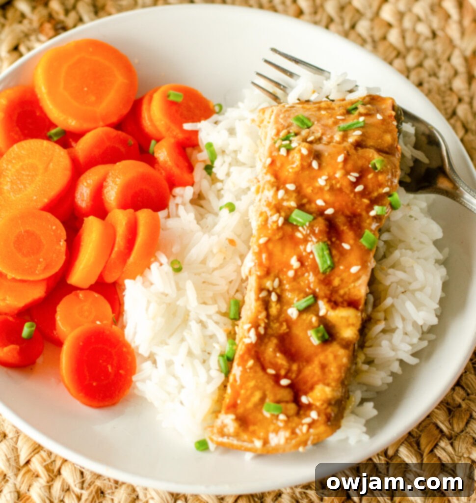 Cooked Teriyaki Salmon served with steamed carrots and a sprinkle of fresh herbs