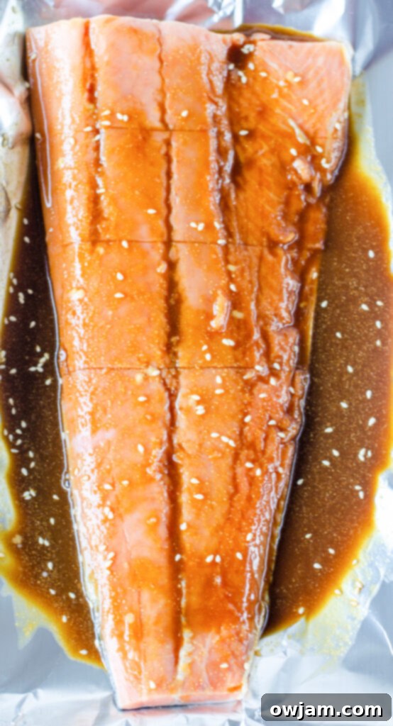 Raw salmon fillets marinating in homemade teriyaki sauce on a baking sheet, ready for the oven