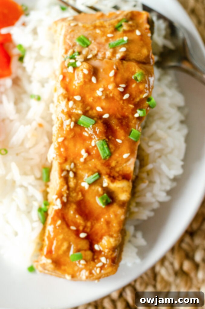 Teriyaki Salmon served with white rice and fresh greens, garnished with sesame seeds