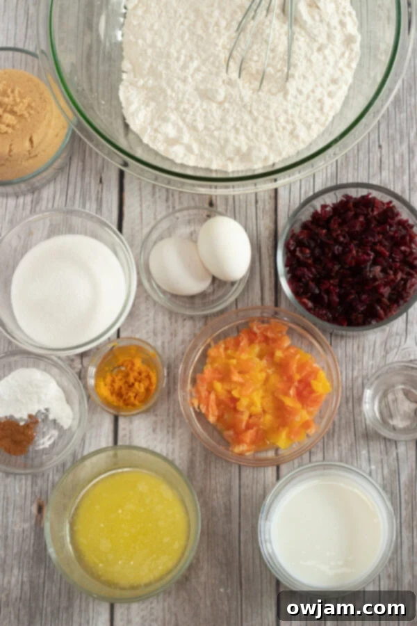 Ingredients for Cranberry Orange Bread laid out on a kitchen counter, including fresh oranges and cranberries in bowls