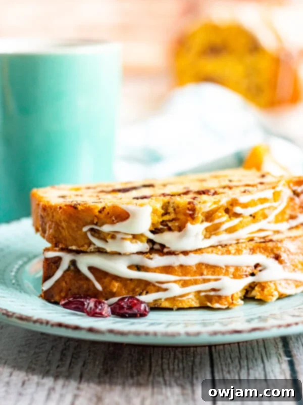 Slice of Cranberry Orange Bread with icing on a plate, garnished with orange zest