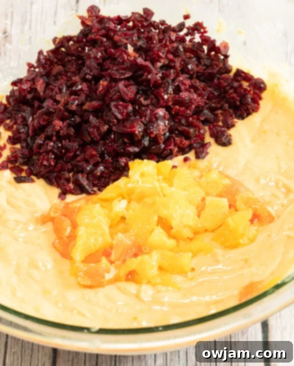 Dried cranberries being folded into the bread batter with a spatula