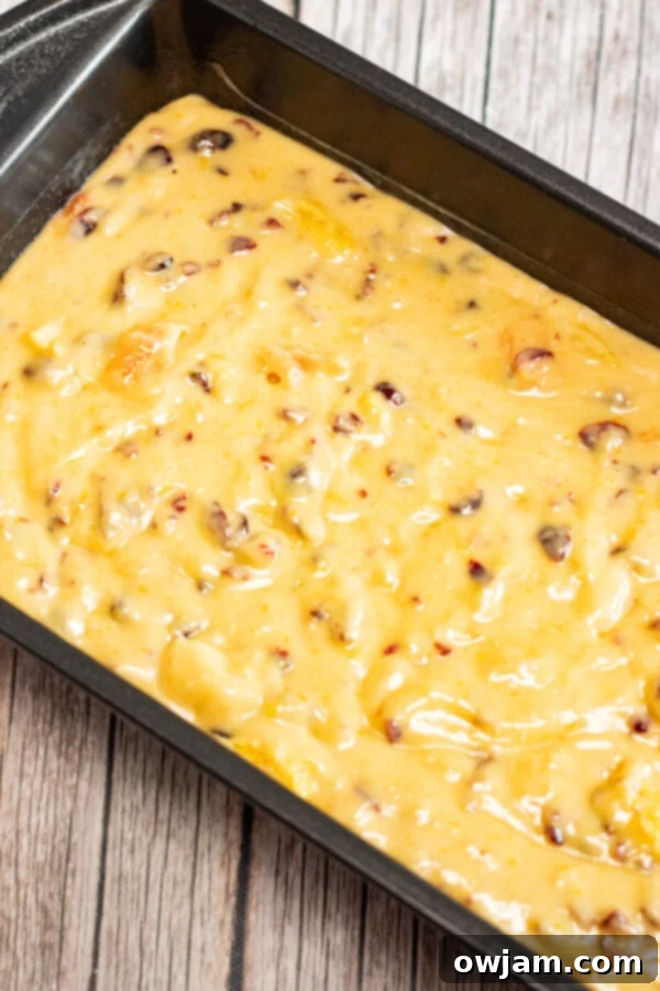 Cranberry Orange Bread baking in a loaf pan, with a golden brown crust