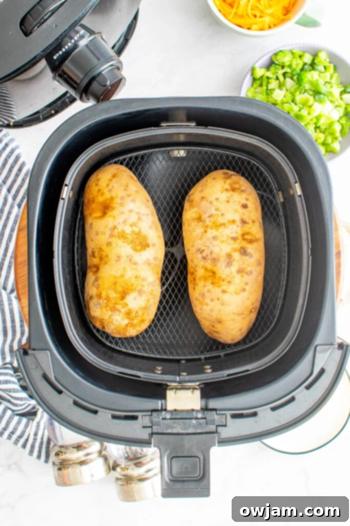 Two whole russet potatoes cooking inside an air fryer basket