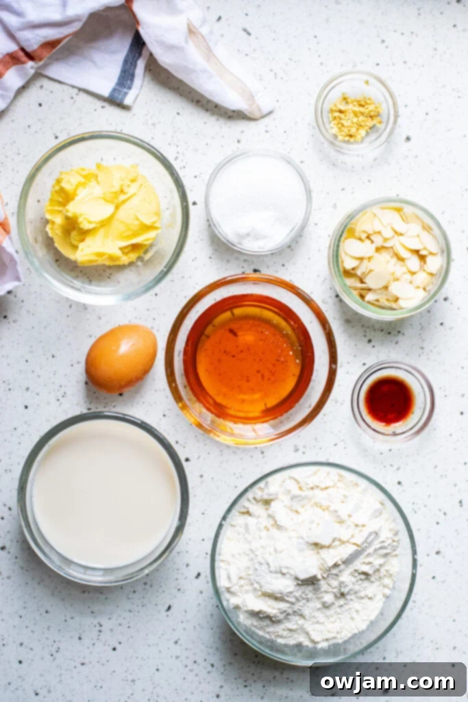 Irresistible Almond Cake 3 Essential ingredients for a light and moist Honey Almond Cake laid out on a kitchen counter, including sliced almonds, fresh ginger, and a jar of honey