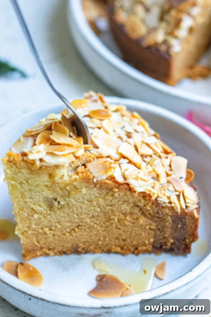 Irresistible Almond Cake 10 A delectable slice of Honey Almond Cake placed on a plate with a fork beside it, inviting you to take a bite