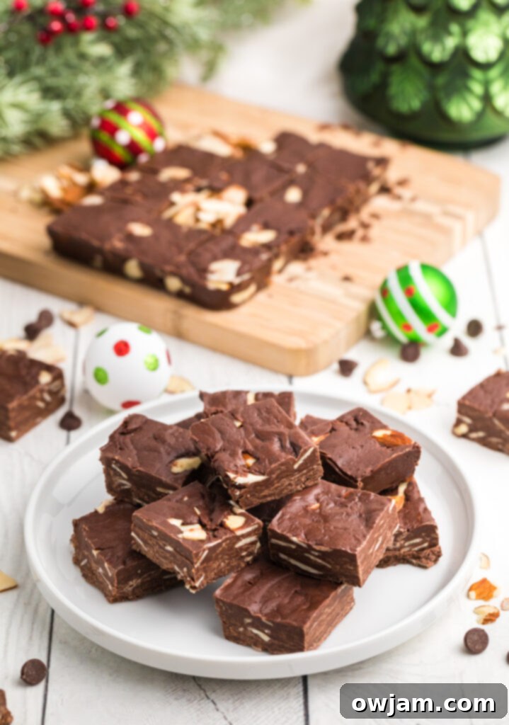 Easy Chocolate Fudge squares on a white plate, garnished with more slivered almonds.