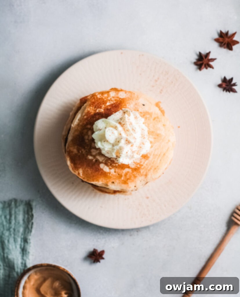 Close-up of Eggnog Pancakes with generous whipped cream and sprinkle of cinnamon