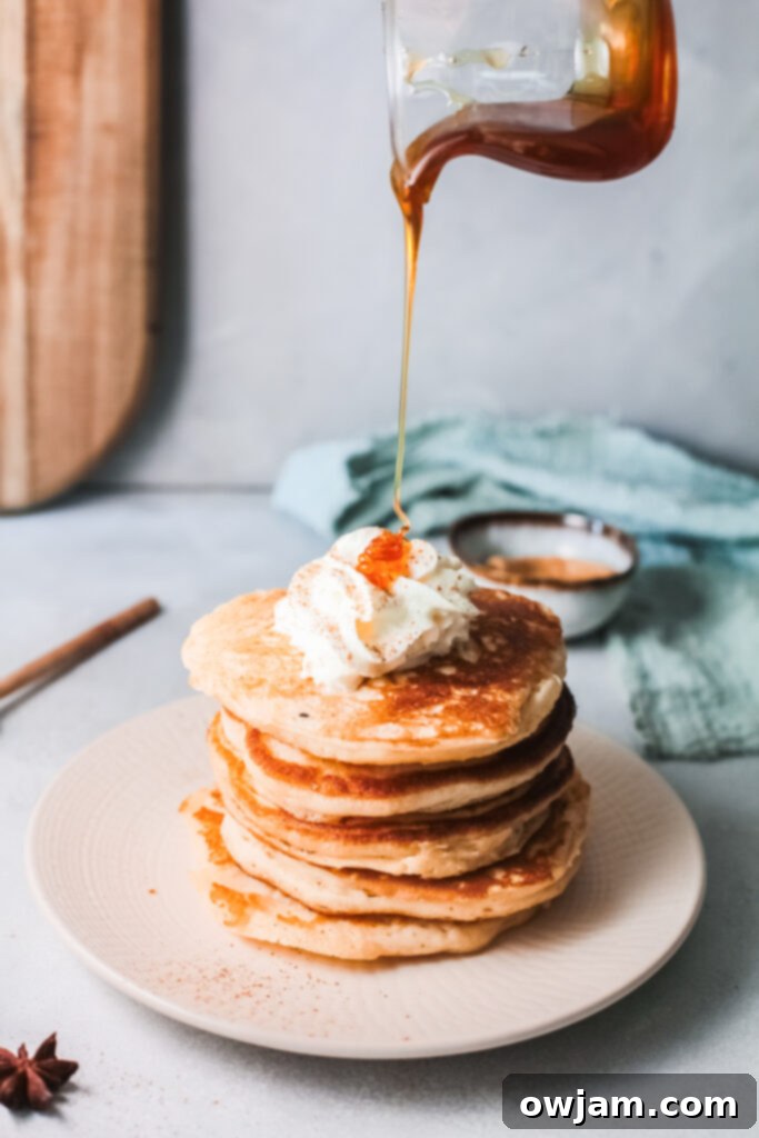 Stack of Eggnog Pancakes with syrup and a dusting of powdered sugar