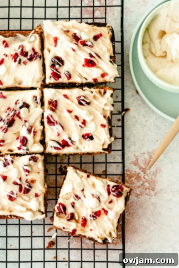 A tray of Cranberry Bliss Bars, still in the pan, cooling on a wire rack after baking and frosting.