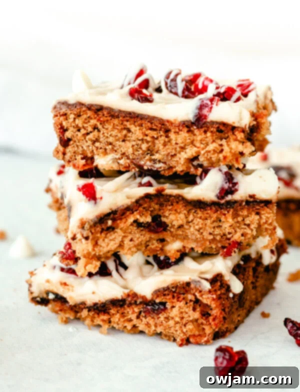 A stack of beautifully frosted and drizzled Cranberry Bliss Bars, ready for serving.