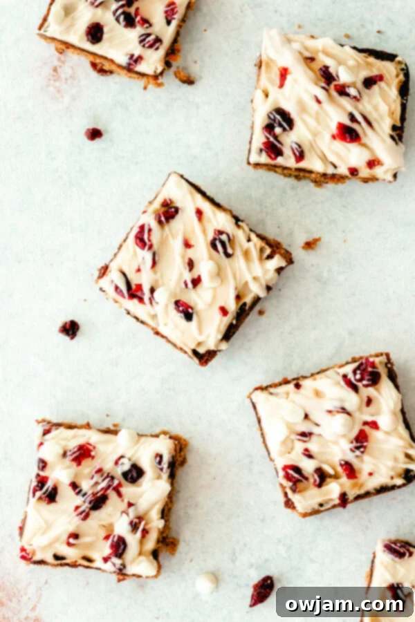 Sliced Cranberry Bliss Bars, showing the distinct triangular shape and festive topping, arranged on a white serving board.