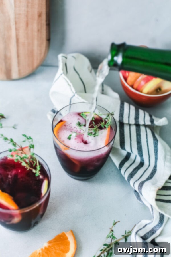 Your New Favorite Red Sangria 3 Red Sangria in a pitcher with champagne being poured into a glass