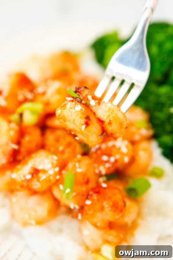 Honey Garlic Sriracha Shrimp with fork, highlighting a single shrimp coated in a glossy sauce.