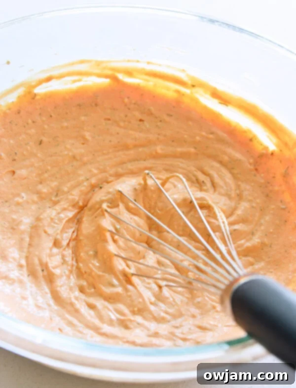 The Ultimate Buffalo Chicken Dip 7 Whisking together cream cheese, sour cream, hot sauce, and spices in a mixing bowl