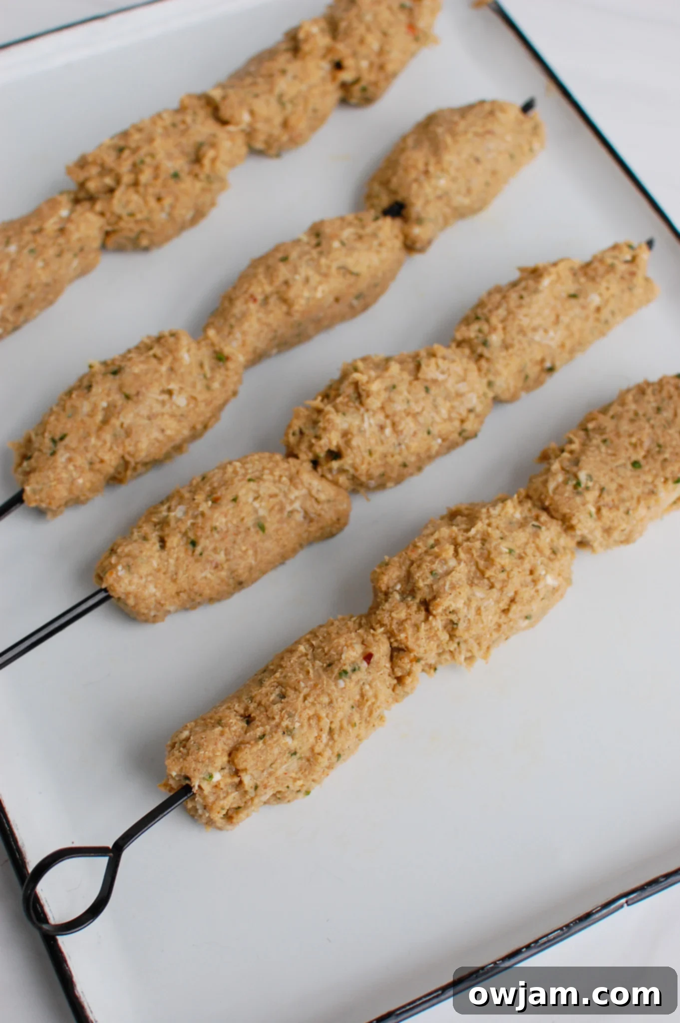Chicken Meatballs 6 Raw Chicken Kofta formed onto metal skewers, ready for cooking.