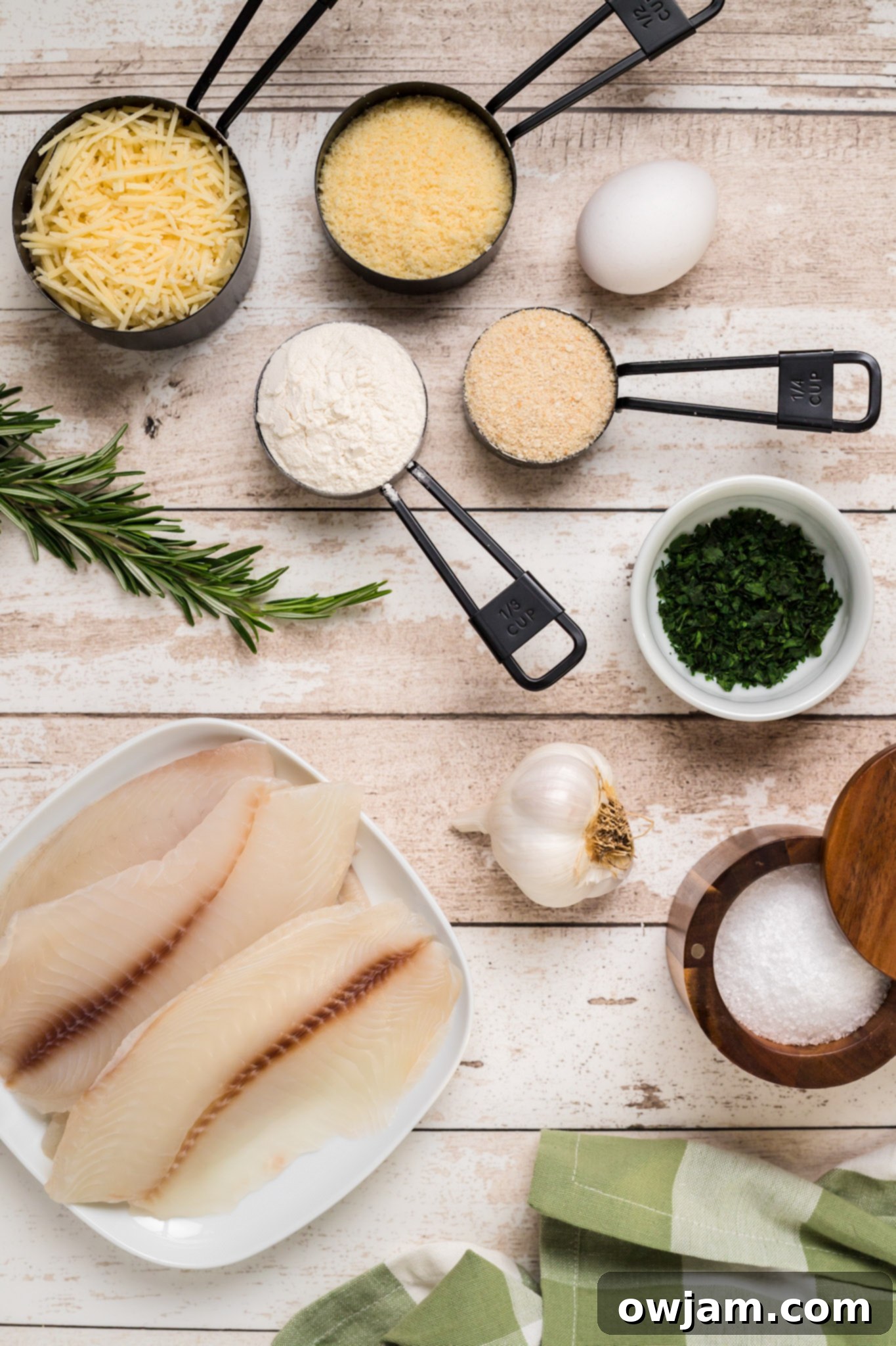 Crispy Parmesan Tilapia 3 All ingredients laid out for Parmesan Crusted Tilapia, including fresh tilapia fillets, Parmesan cheese, breadcrumbs, flour, herbs, garlic, and egg.