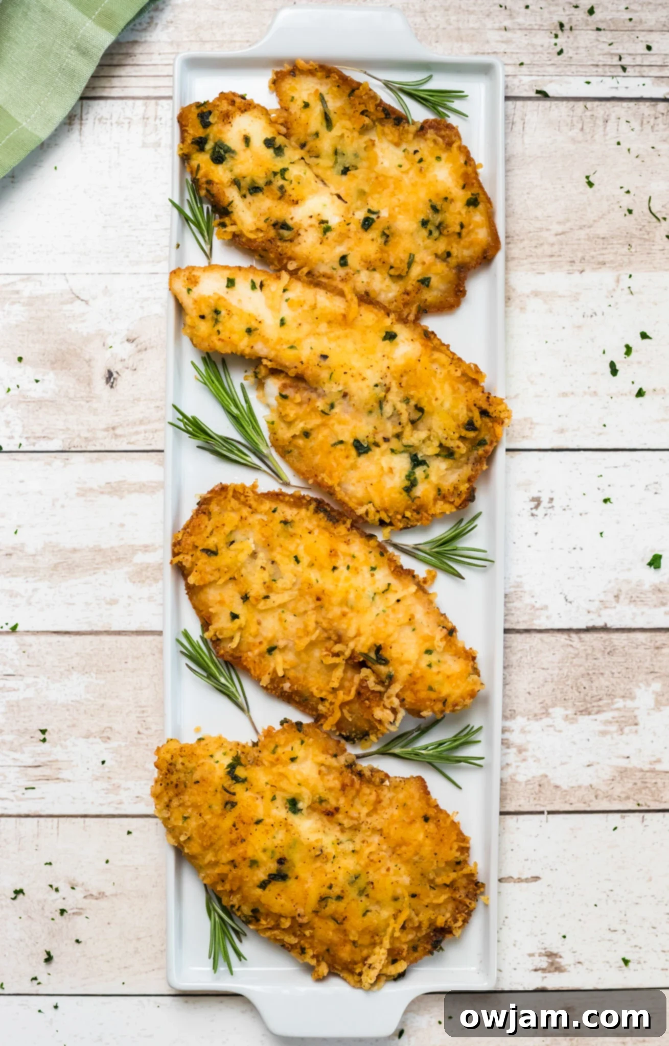 Crispy Parmesan Tilapia 9 Close-up of Parmesan Crusted Tilapia garnished with fresh rosemary, highlighting the crispy texture and appealing herbs.