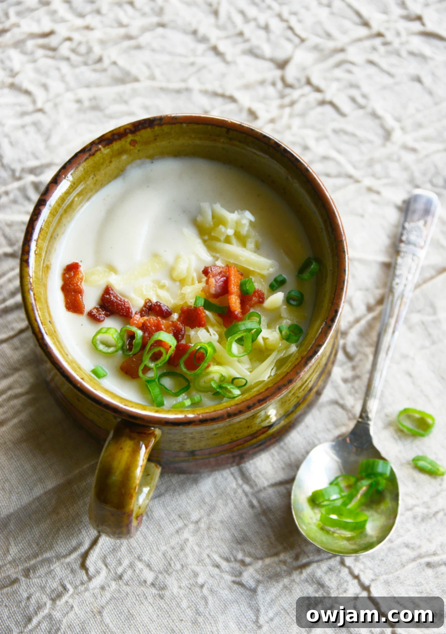 Instant Pot Cauliflower Soup with spoon and green onions on top.