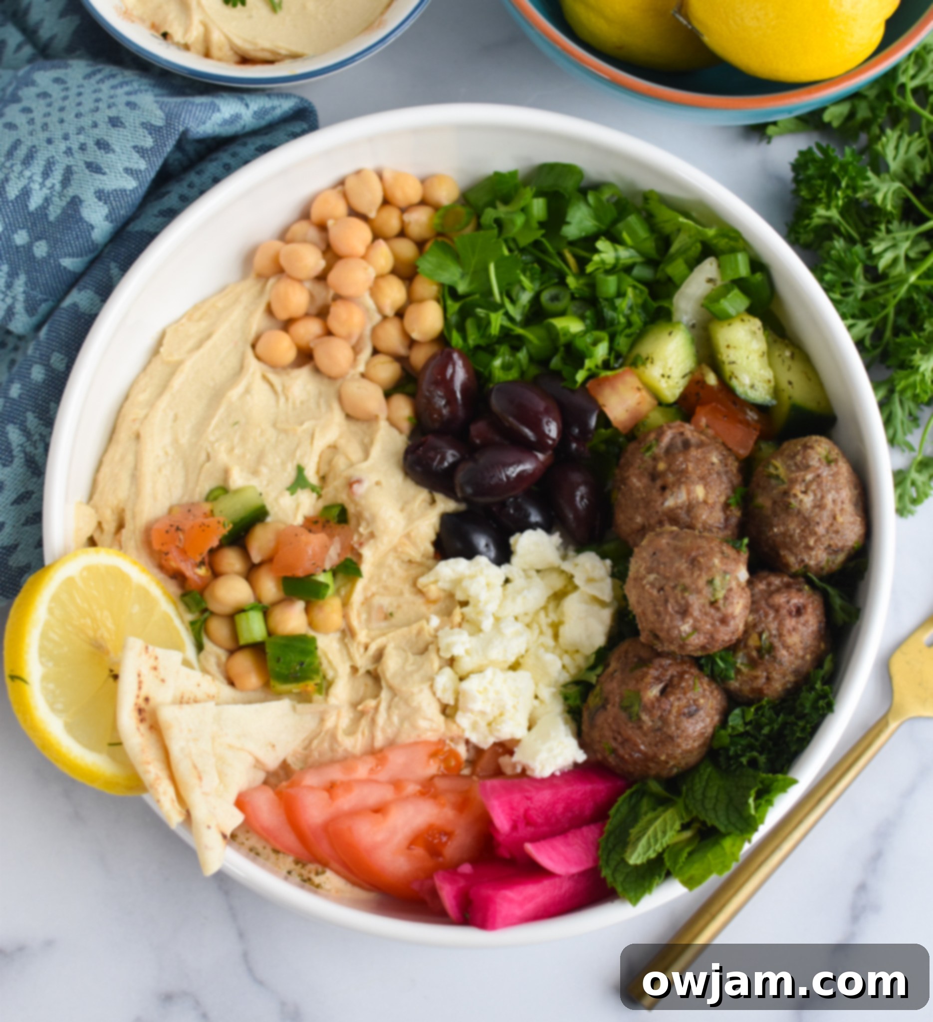 Lamb Kofta with hummus, feta cheese, tomatoes, cucumbers and green onions. A vibrant and healthy meal.