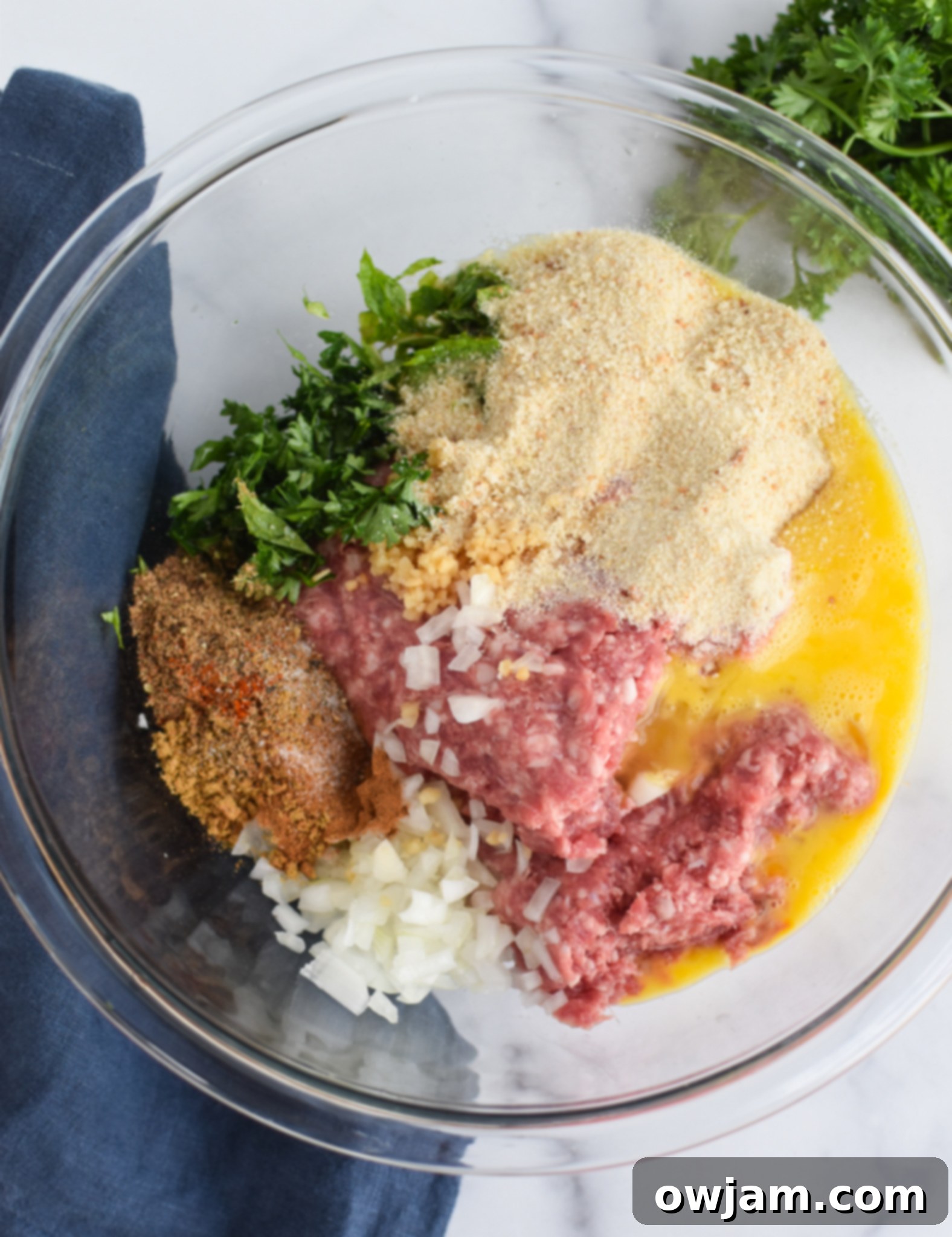 Lamb Kofta ingredients in a mixing bowl, being hand-mixed.