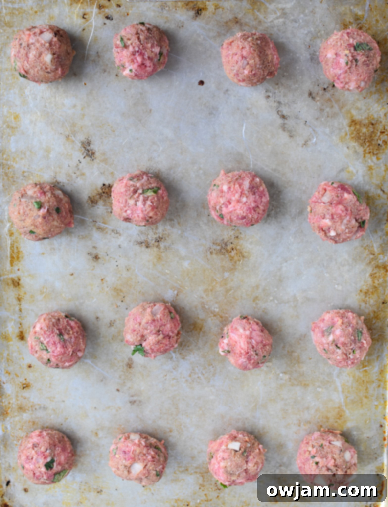 Raw Lamb Kofta meatballs on a baking sheet, ready for the oven.