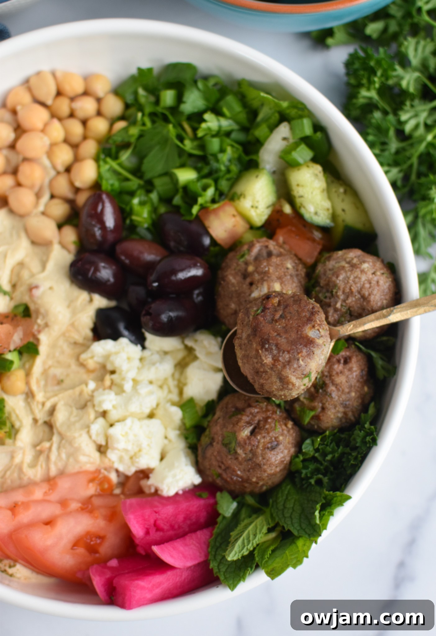 Lamb Kofta in a hummus bowl with a fork, ready to eat.