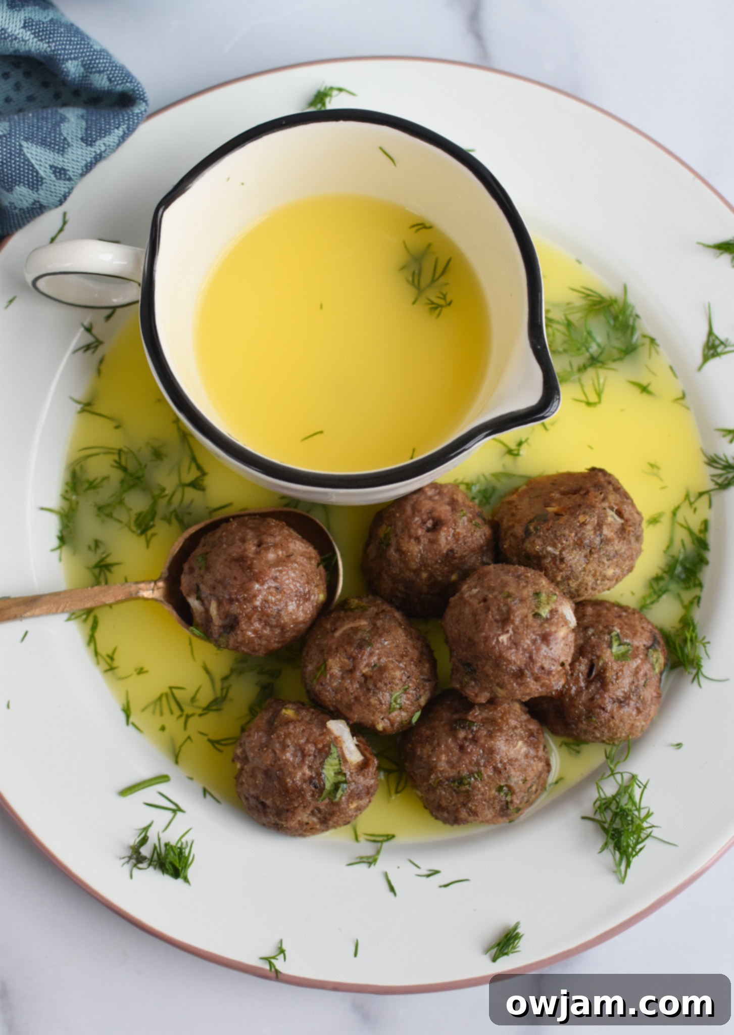 Lamb Kofta with lemon sauce, garnished with fresh herbs.