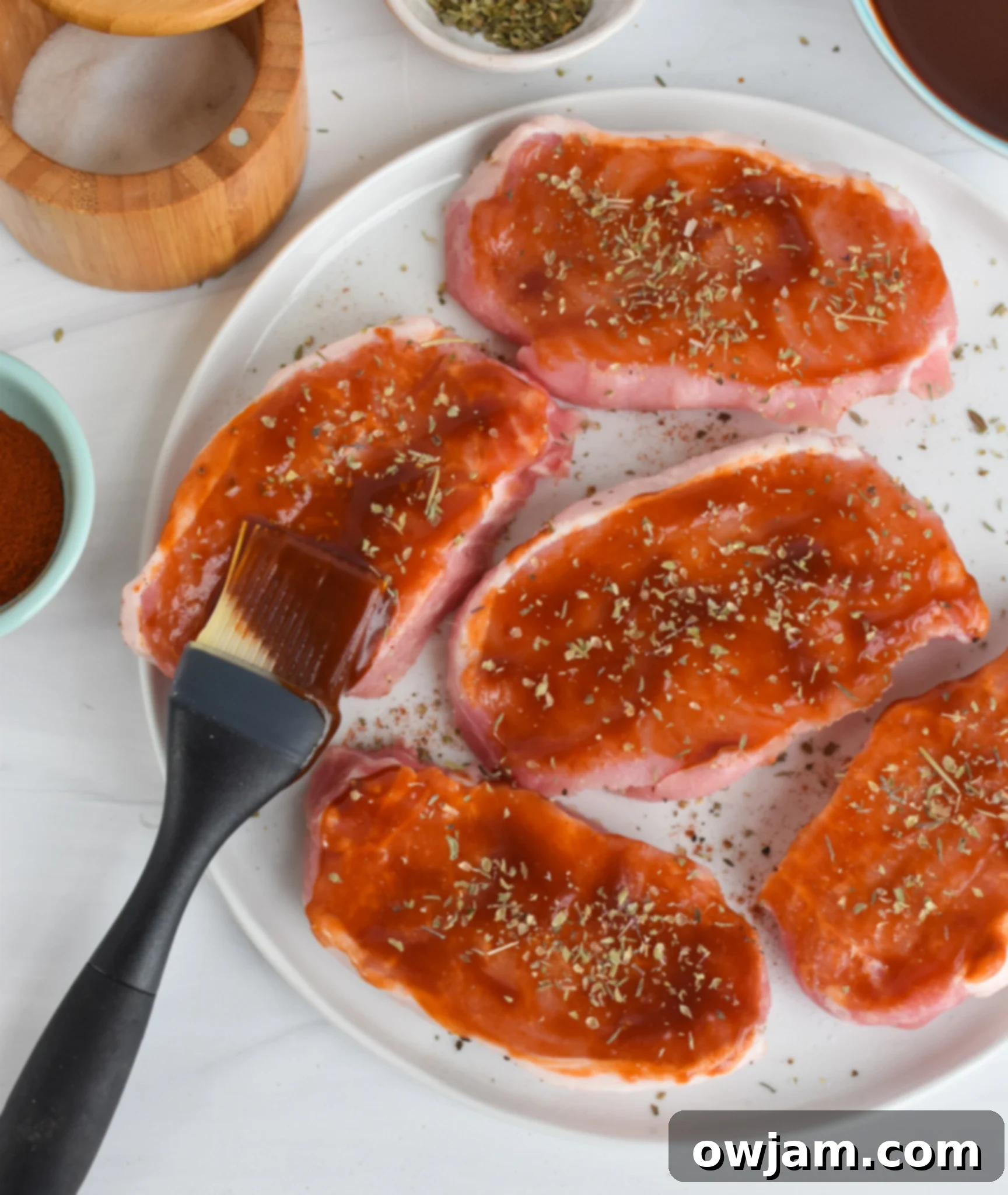 Mouthwatering BBQ Baked Pork Chops 4 A brush coating a pork chop with rich, homemade BBQ sauce.