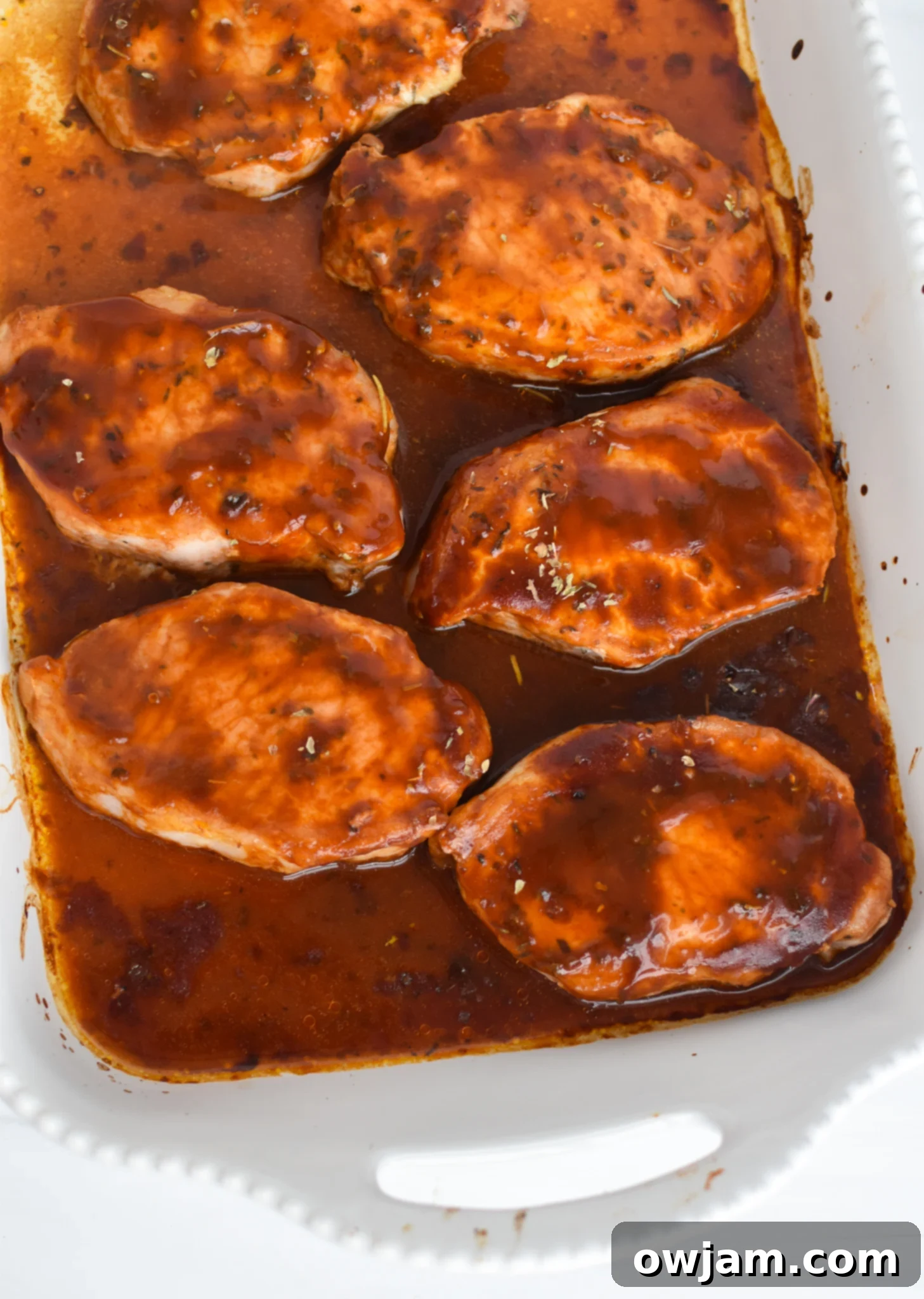 Mouthwatering BBQ Baked Pork Chops 5 Oven-baked BBQ Pork Chops cooking on a baking sheet with a wire rack, halfway through baking.