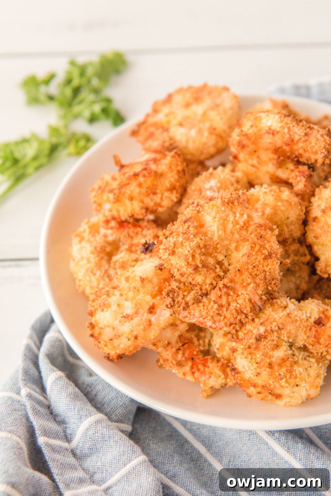 Golden Air Fryer Coconut Shrimp 4 Air Fryer Coconut Shrimp on a plate on a napkin.
