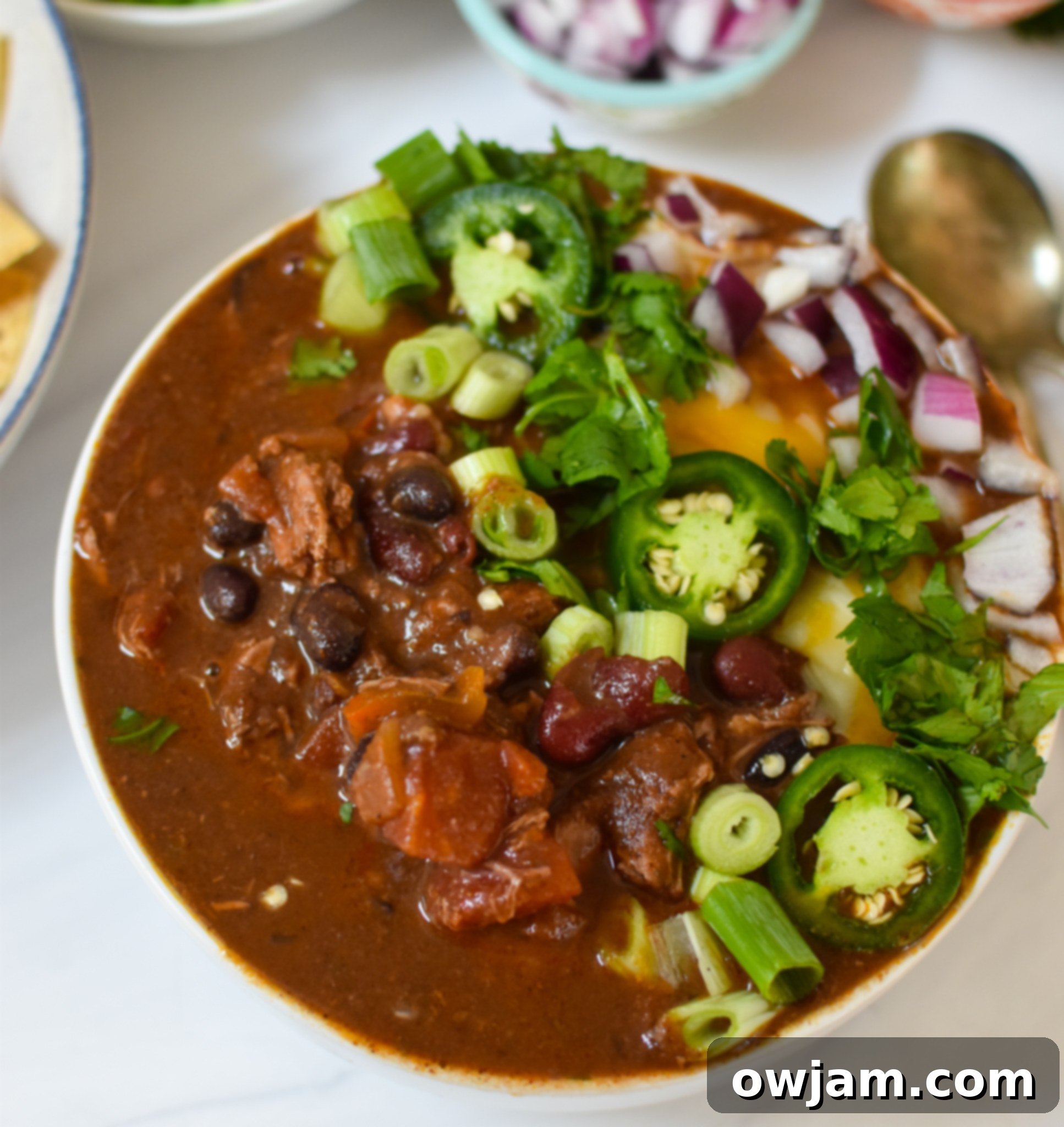 Hearty Chili Con Carne 5 Chili Con Carne served in a bowl with various garnishes like cheese, sour cream, and jalapeños.