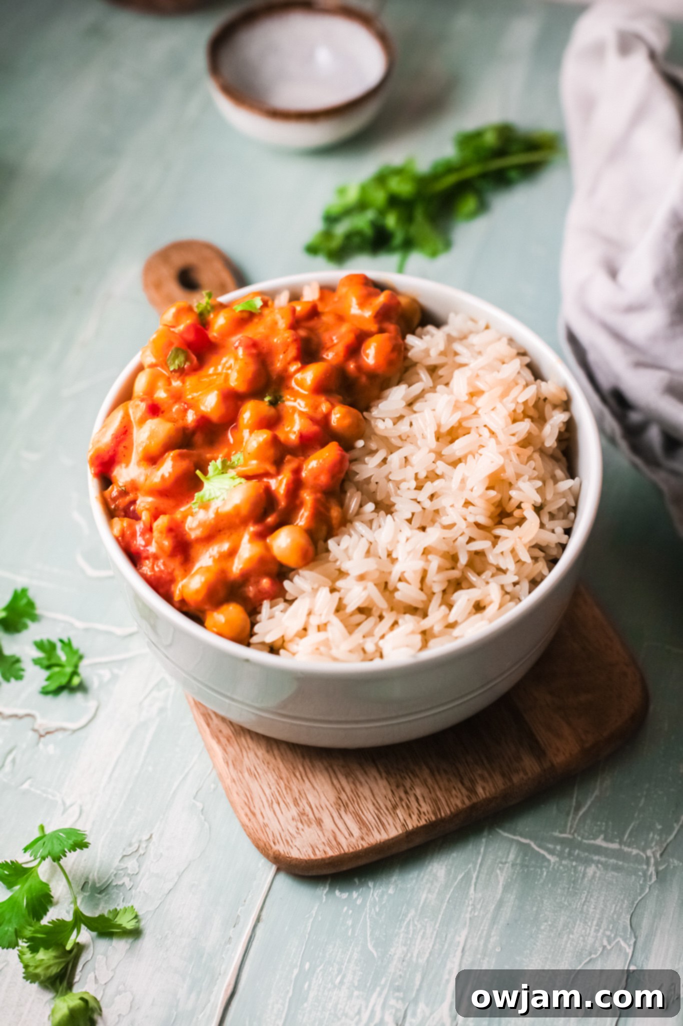 Chickpeas with Curry in a bowl with rice, garnished with fresh cilantro.