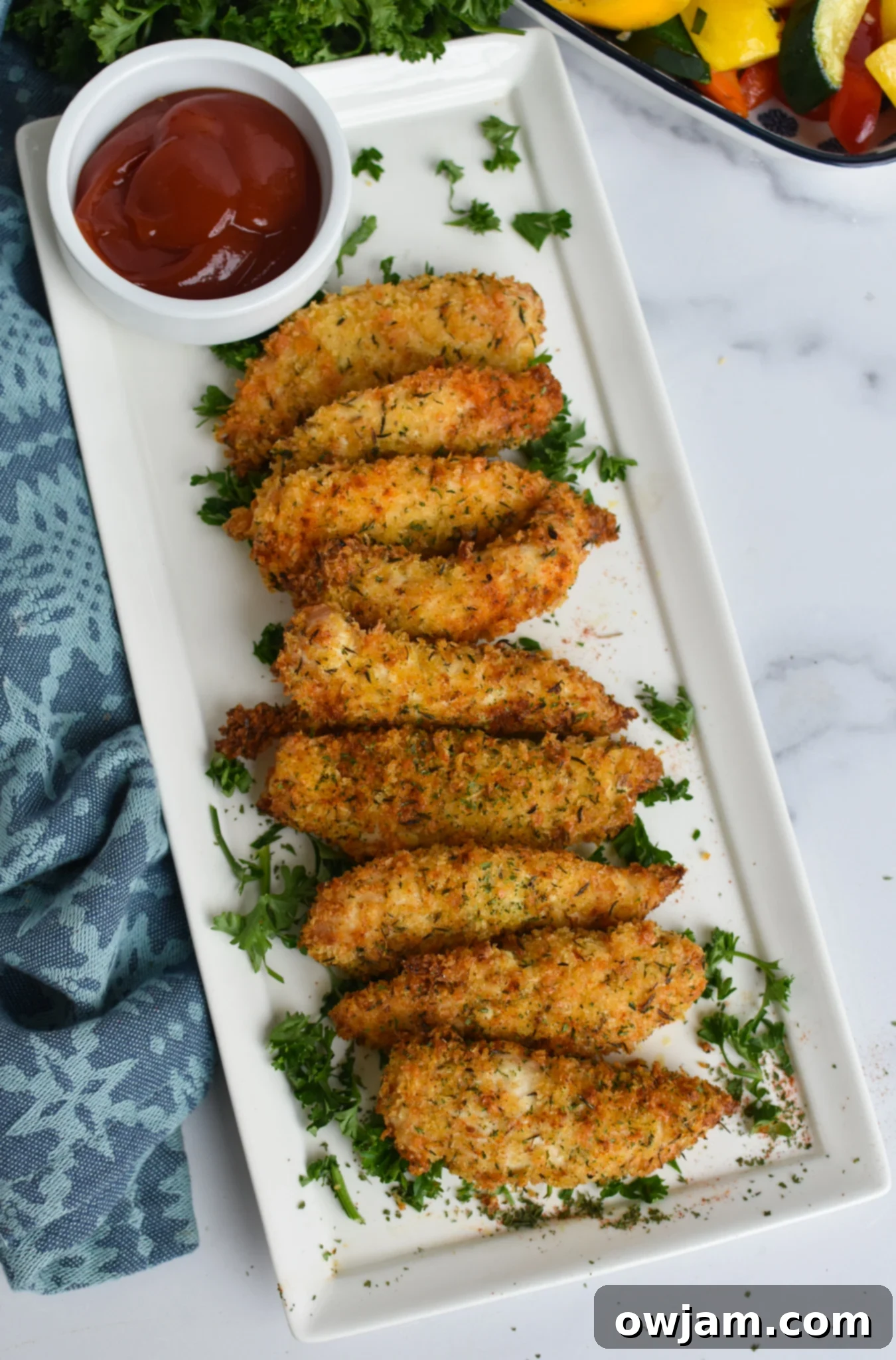 Crispy Air Fryer Chicken Tenders 3 Air Fryer Chicken Tenders arranged on a white long platter.