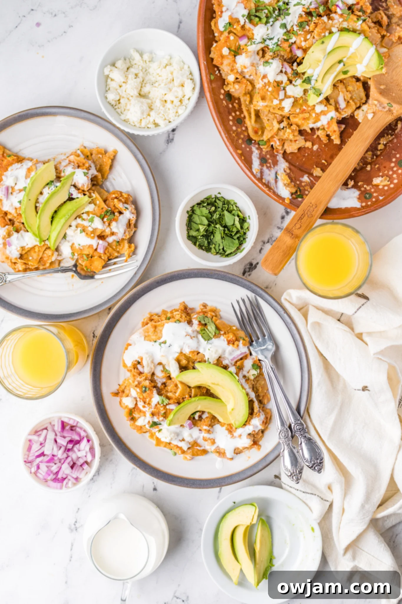 Traditional Red Chilaquiles 7 A plate of Chilaquiles Rojos with avocado and a glass of orange juice on the side, ready for breakfast.