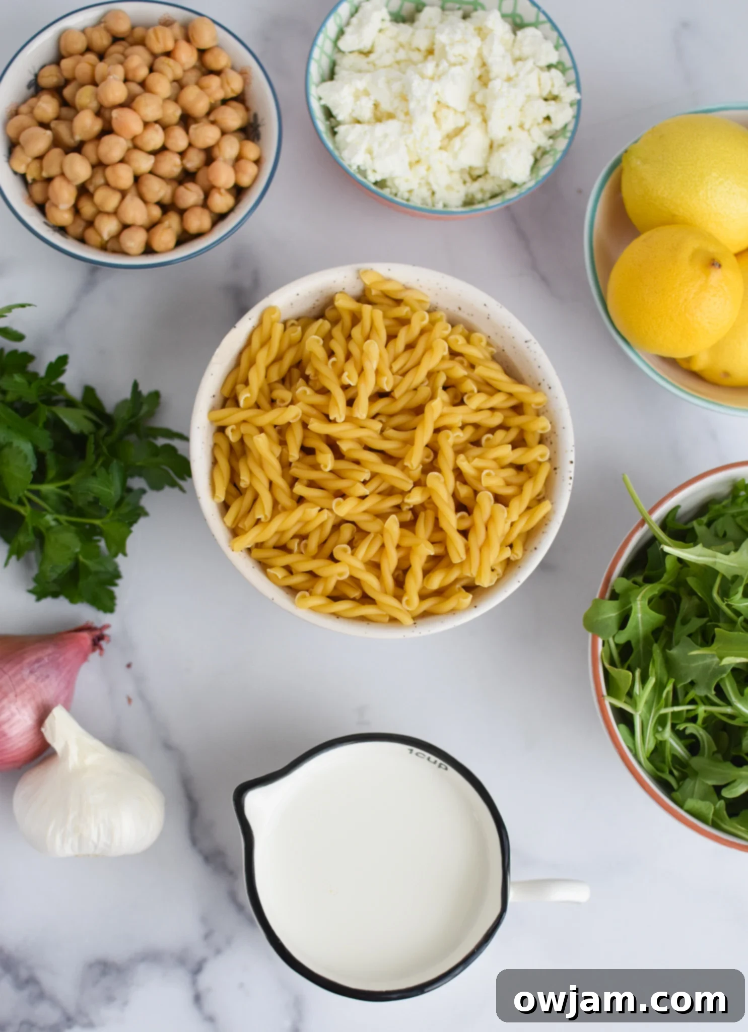 Fresh ingredients for Chickpea Pasta Recipe with Feta, including lemon, feta, and arugula.