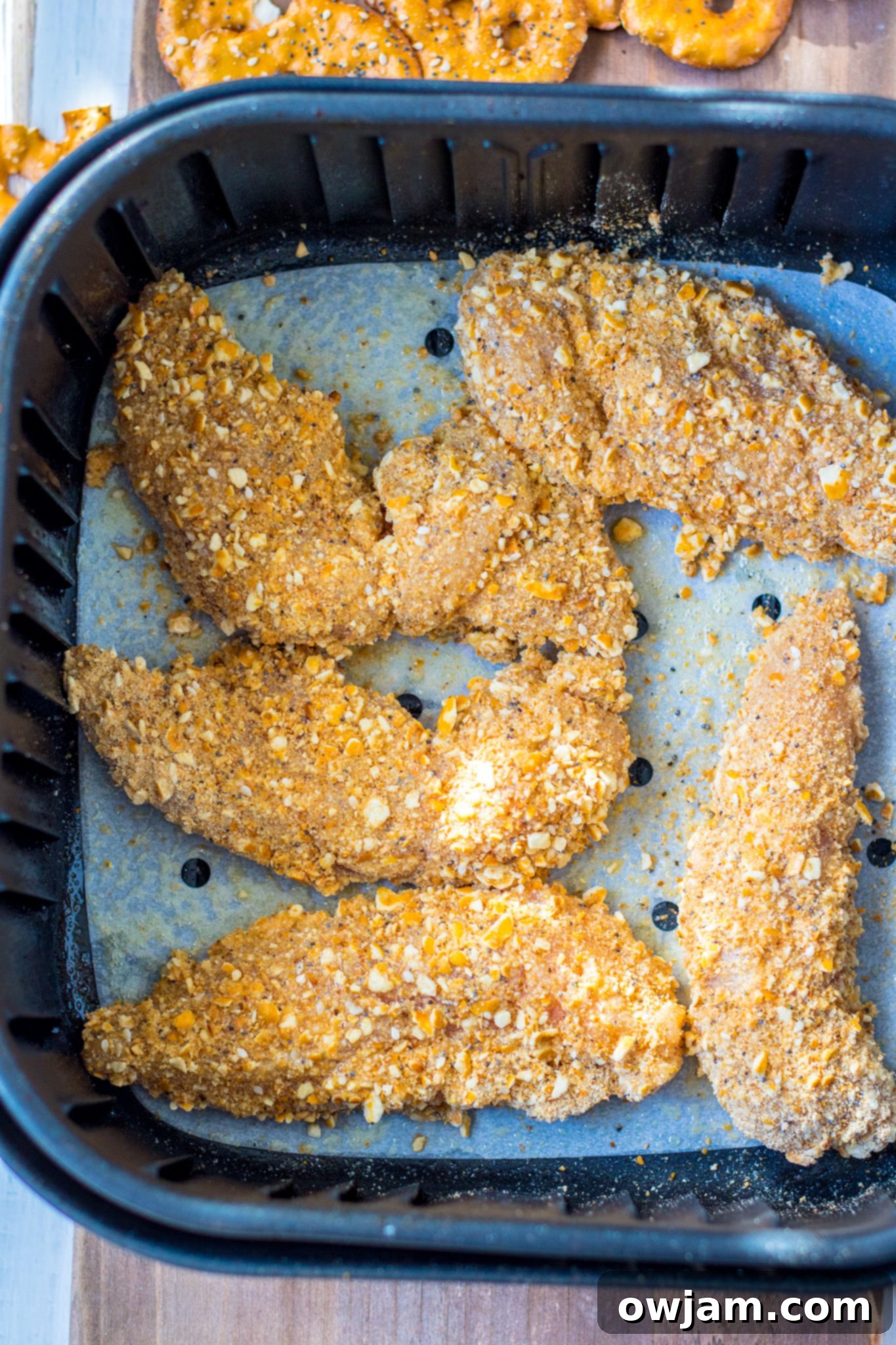 Crunchy Pretzel Chicken 7 Crispy Pretzel Crusted Chicken Tenders cooking inside an air fryer basket.