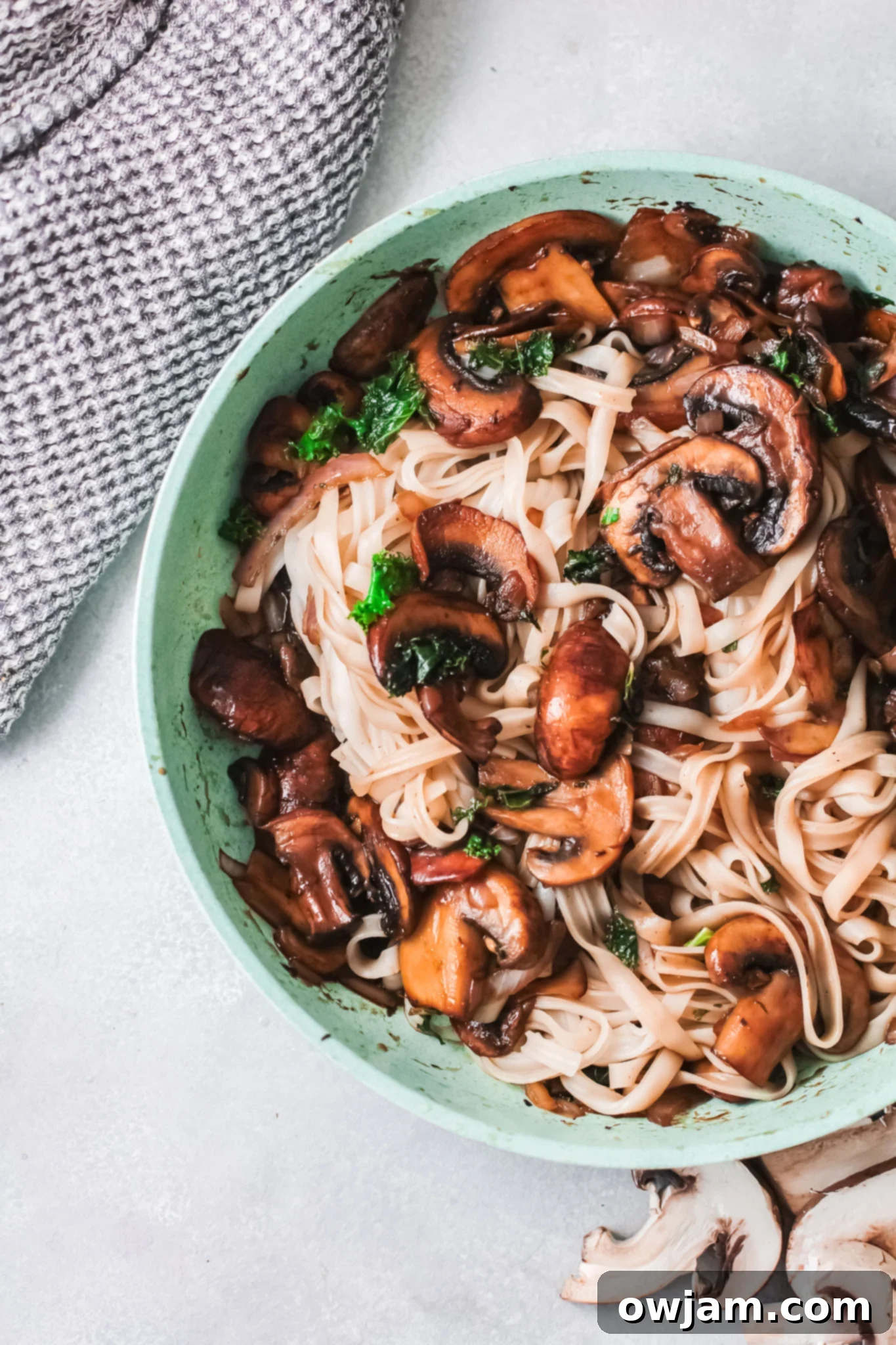 Delicious Korean Noodles in Minutes 3 Easy Korean Noodles Recipe cooking in a teal skillet, showing mushrooms and kale.
