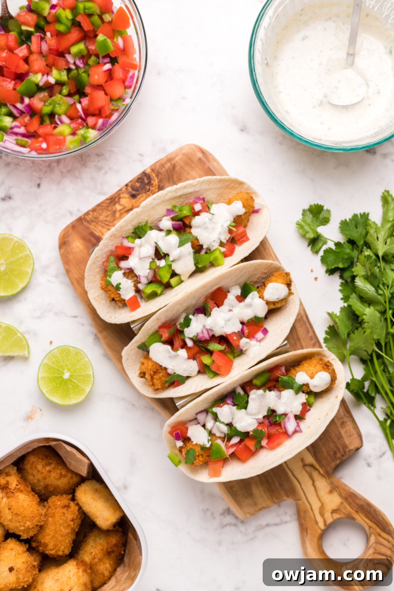 Tilapia Fish Tacos drizzled with creamy lime aioli and garnished with fresh cilantro.