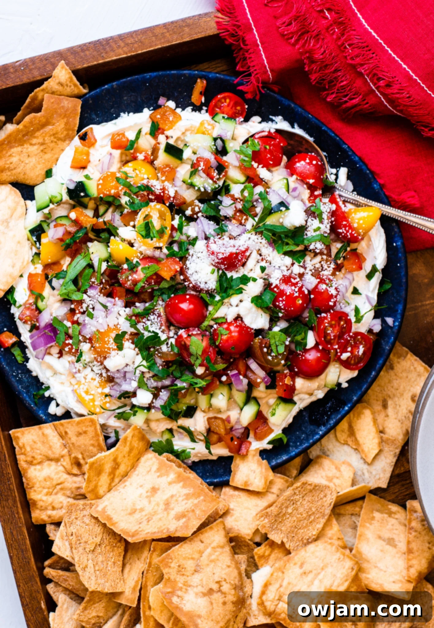 Layered Greek Dip with pita chips, ready to be served.