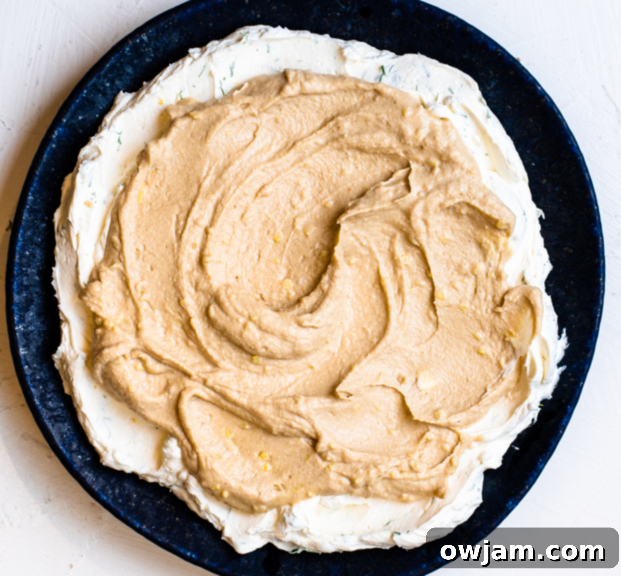 Layered Greek Dip during assembly, showing the hummus layer over Greek yogurt.
