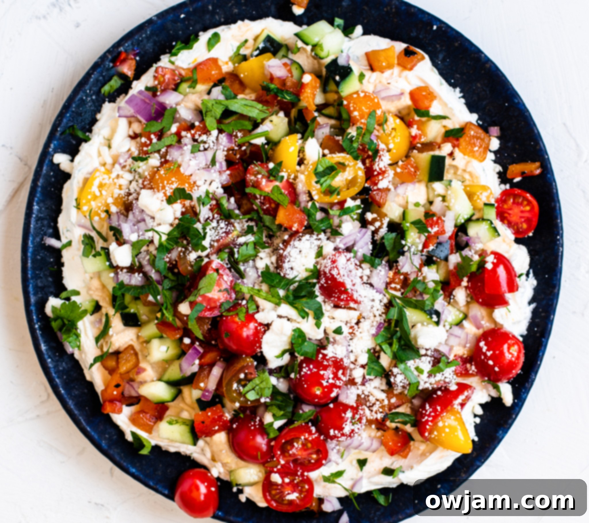 Layered Greek Dip with feta cheese added, before final herbs.