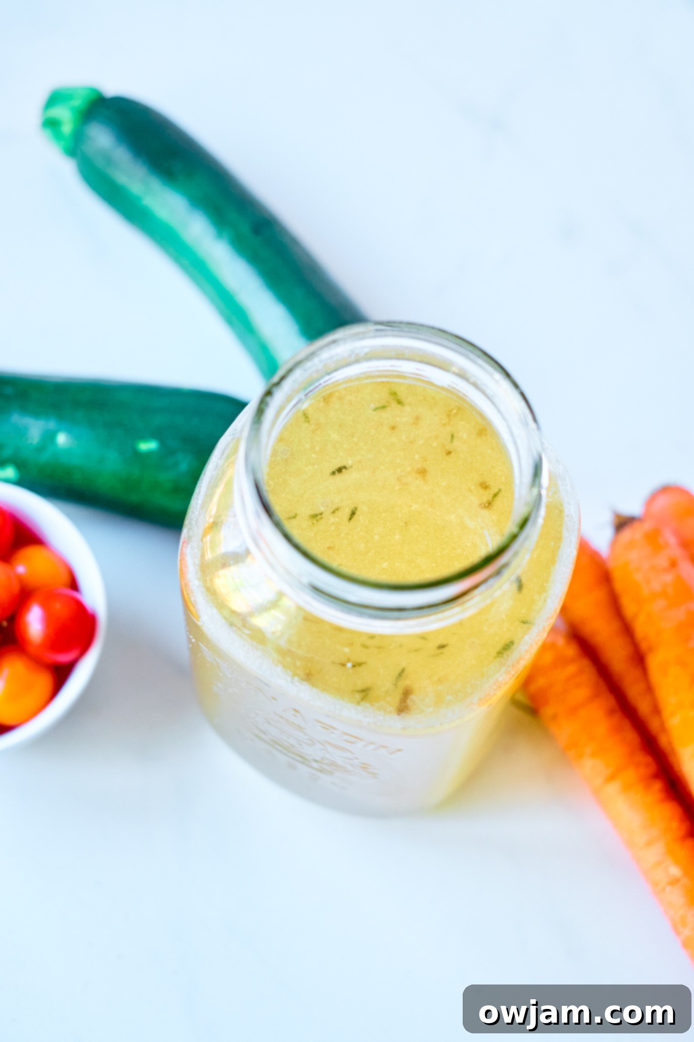 Effortless Homemade Beef Bone Broth 4 Freshly made Easy Beef Bone Broth cooling in a glass jar on a kitchen counter, showcasing its rich golden hue.