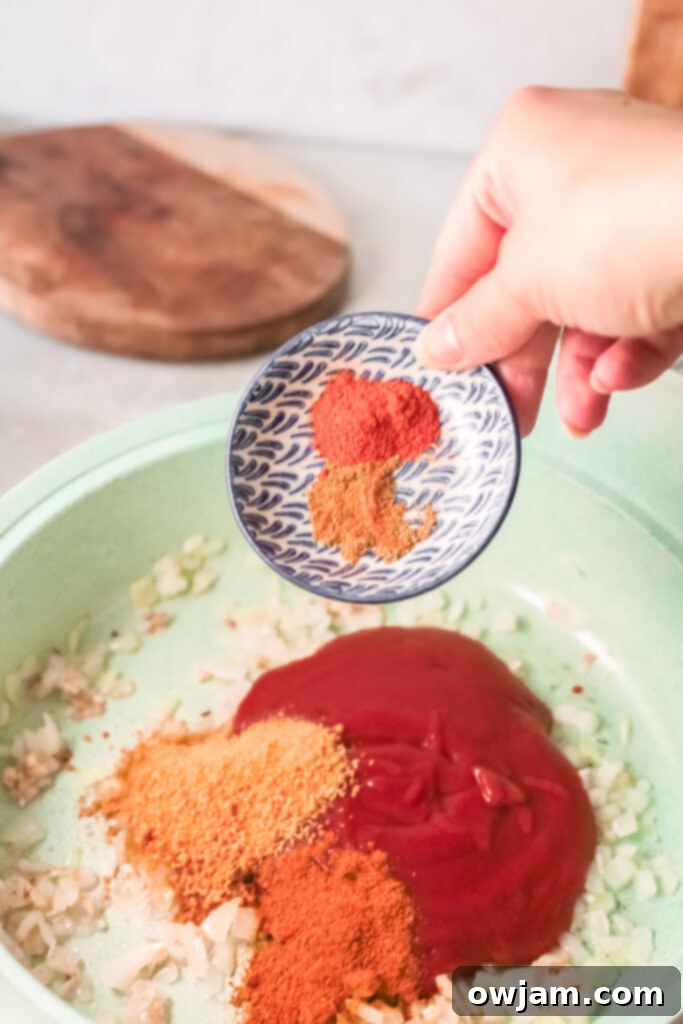 Spices being sprinkled into the tomato sauce mixture for Red Lentil Curry.
