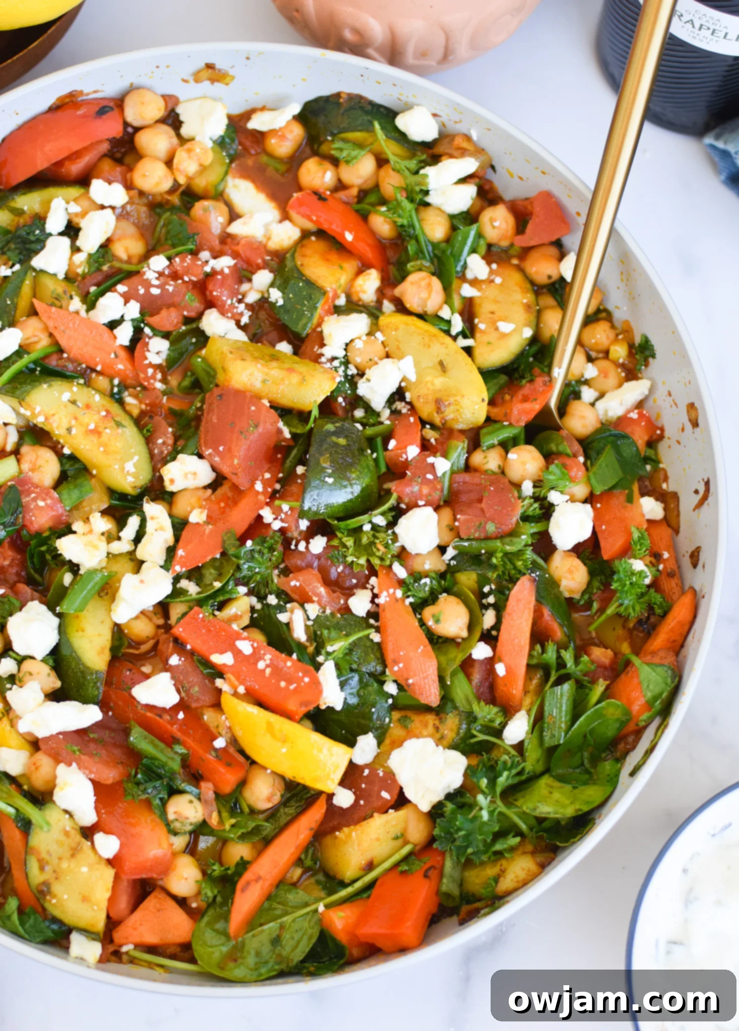 Vibrant Mediterranean Chickpea Skillet 3 Close-up of Mediterranean Chickpea Skillet with a golden spoon, highlighting its warm, inviting colors and textures.