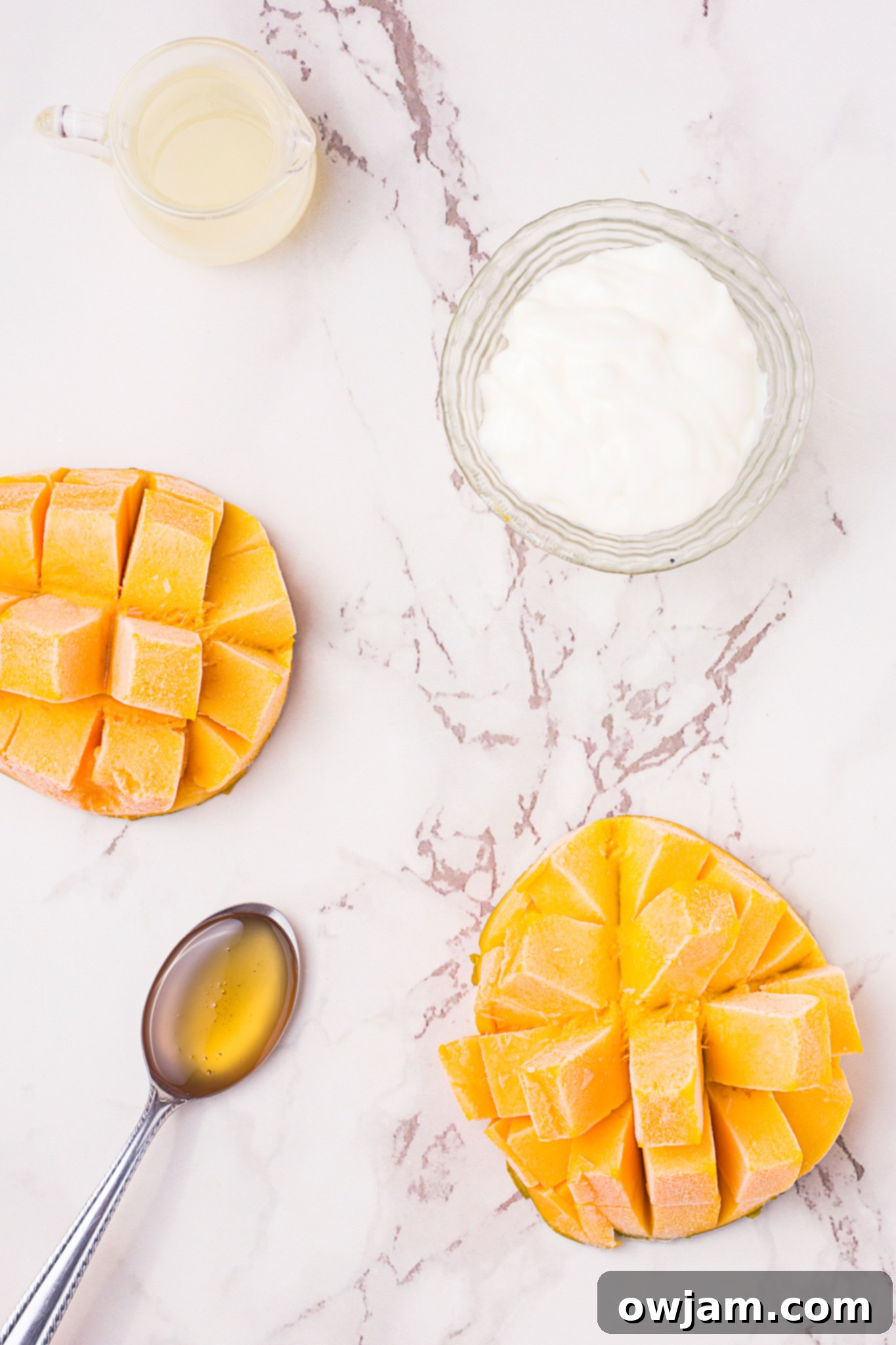 Mango Lassi ingredients laid out: fresh mango chunks, yogurt, honey, milk, and a pinch of cardamom powder.