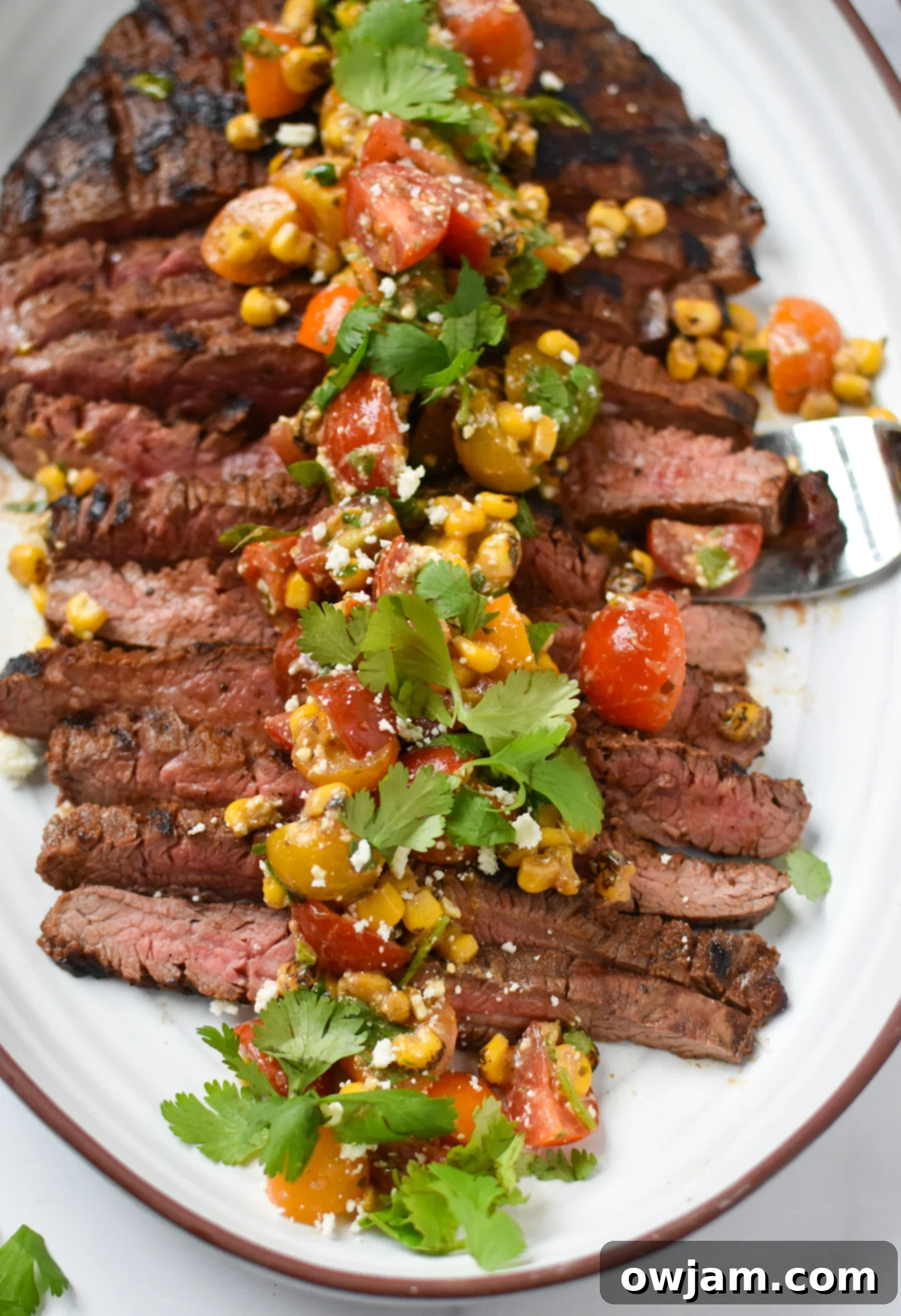 Grilled Flank Steak with Dry Rub on white platter. 