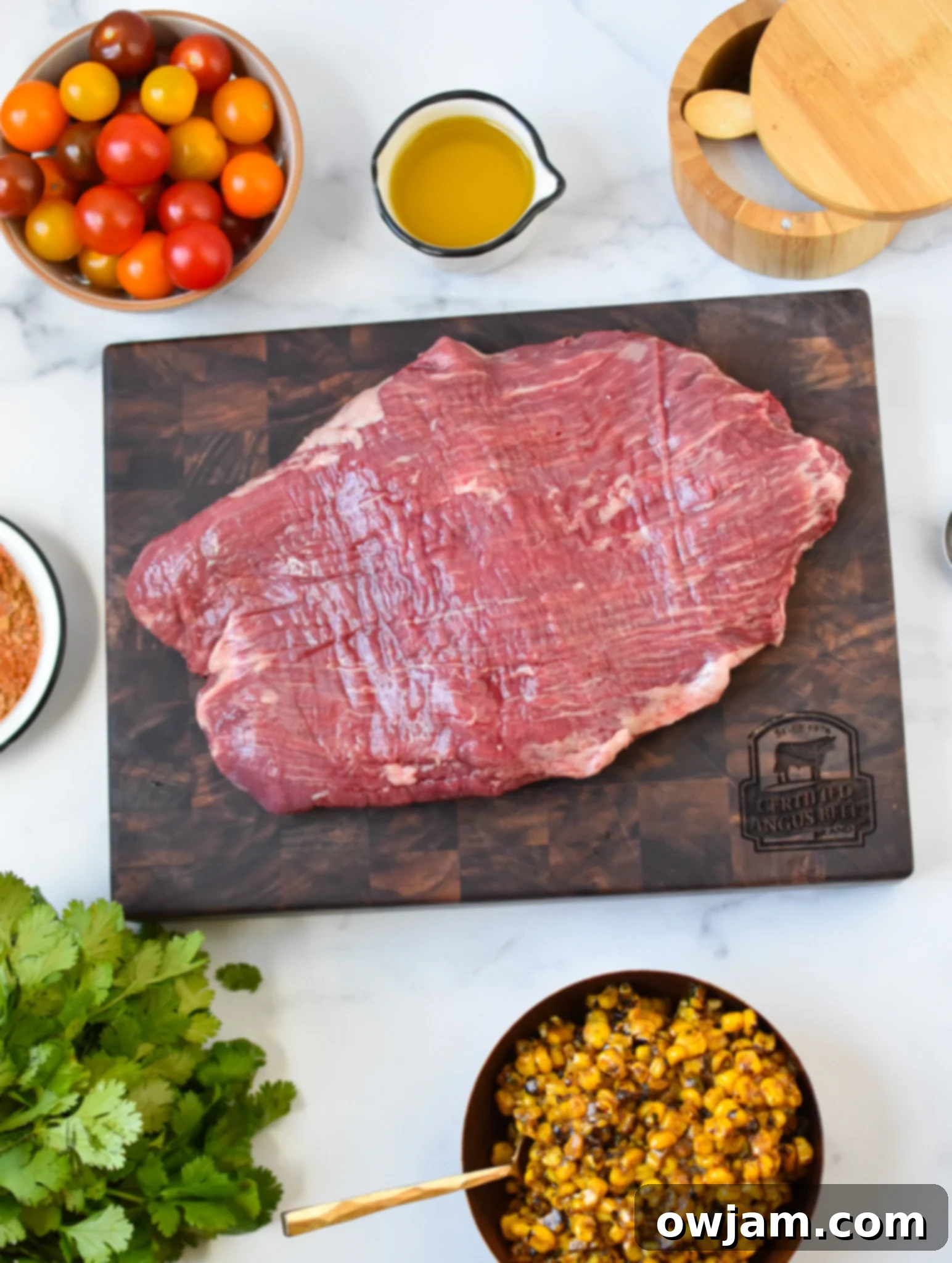 Grilled Flank Steak with Dry Rub ingredients with flank steak on cutting board. 