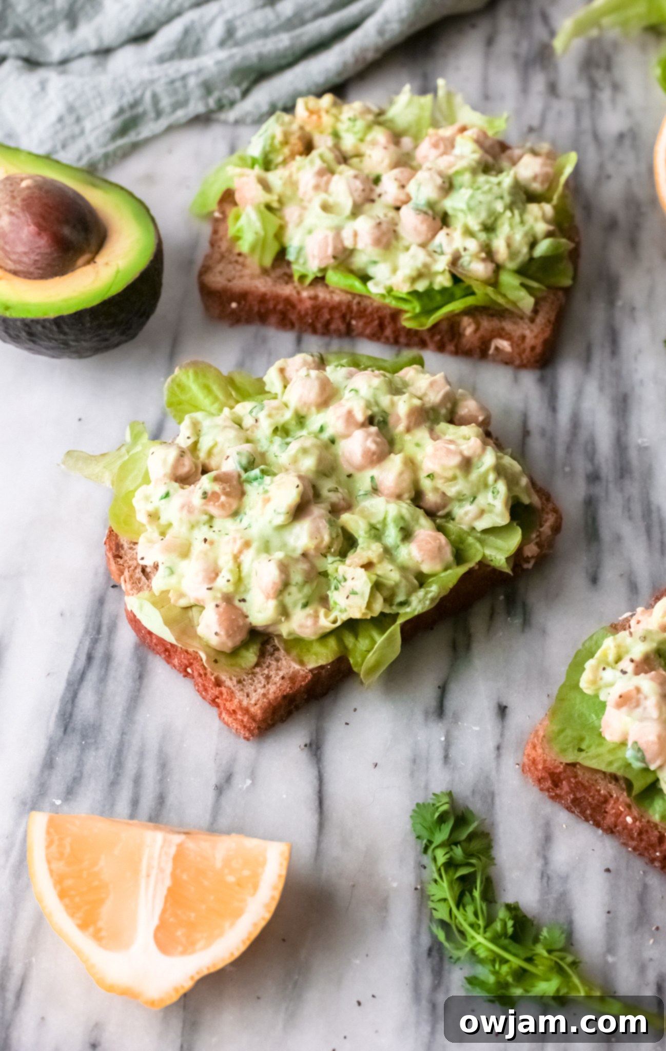 Chickpea Salad Sandwich served on bread, garnished with fresh herbs.
