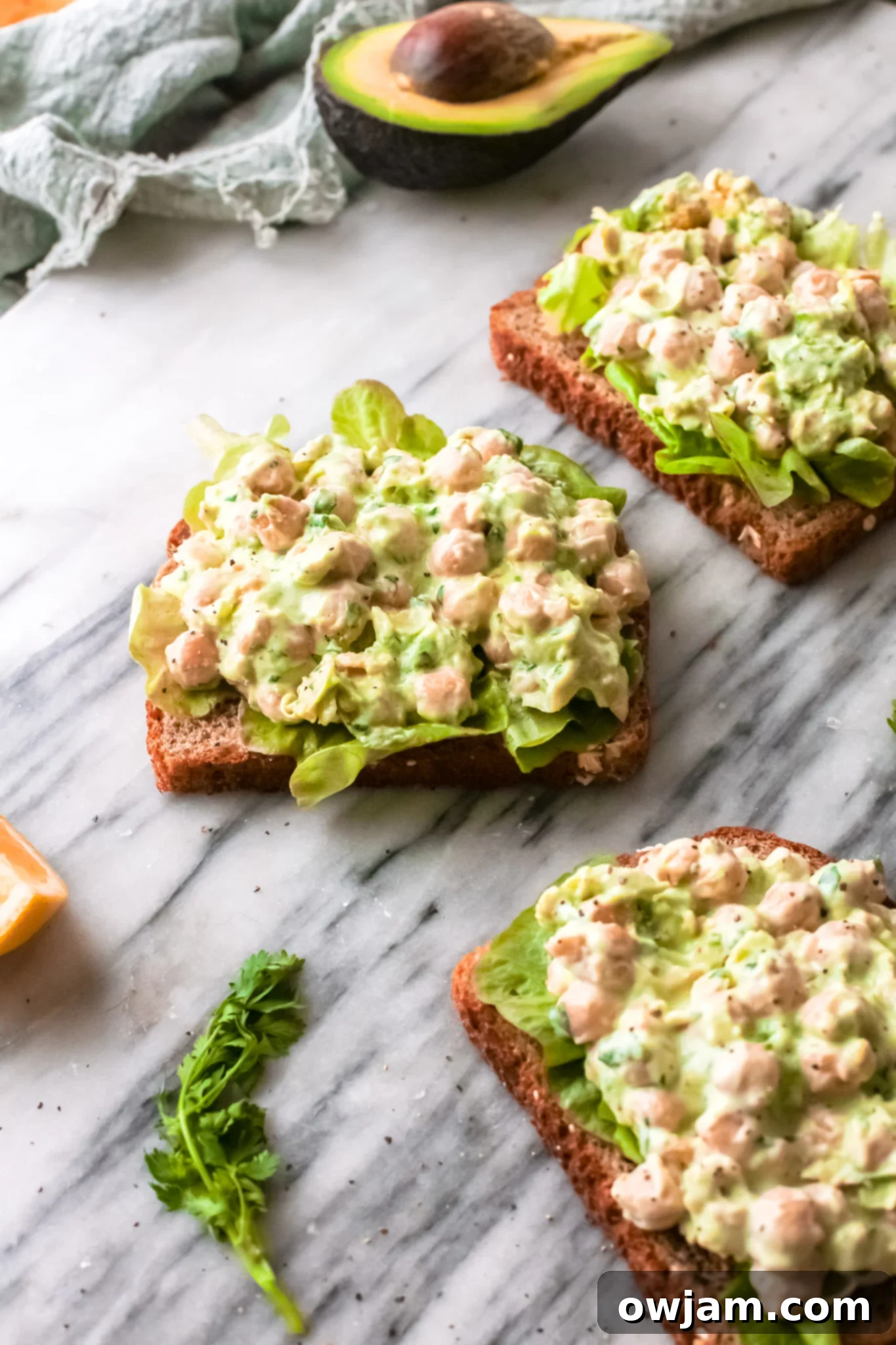The Perfect Easy Chickpea Salad Sandwich 10 Two halves of a Chickpea Salad Sandwich on a marble board, showcasing its vibrant filling.